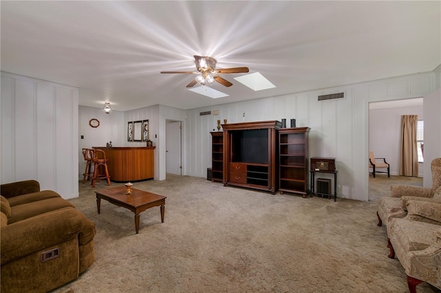 carpeted living room featuring a skylight and ceiling fan