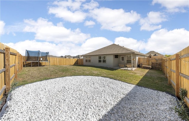 back of property with a lawn, a patio, and a trampoline