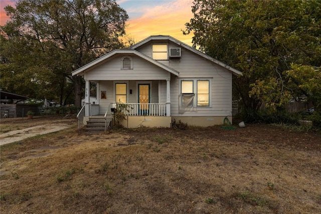 bungalow-style home featuring an AC wall unit and a porch