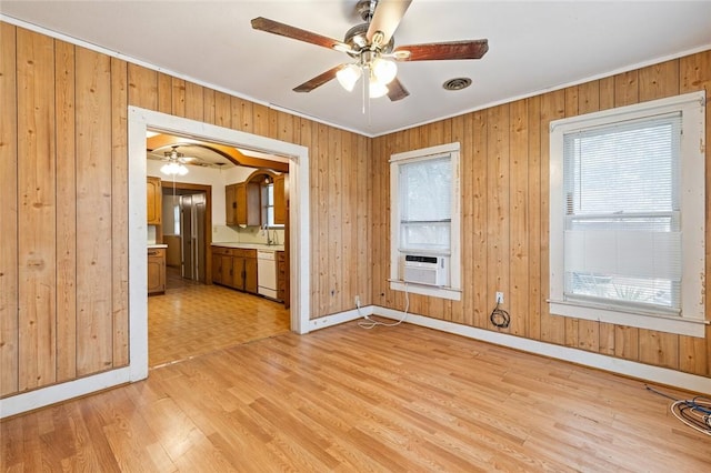 empty room with wood walls, light hardwood / wood-style floors, and ornamental molding