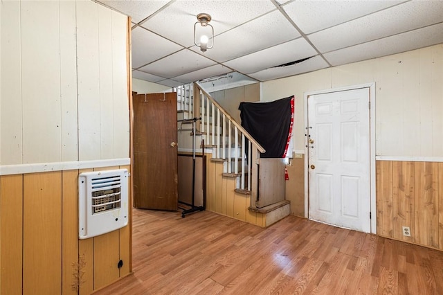 entryway with heating unit, wood walls, a paneled ceiling, and light hardwood / wood-style floors