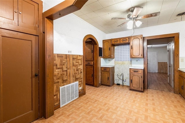 kitchen featuring wooden walls, light parquet floors, and ceiling fan