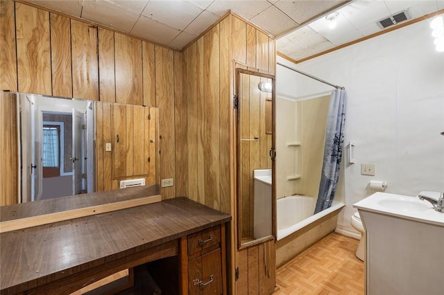 full bathroom with parquet floors, wood walls, toilet, shower / tub combo with curtain, and vanity