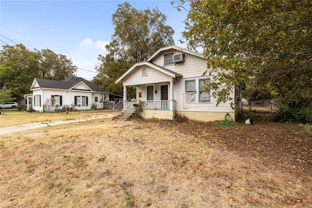 view of front of house featuring a wall unit AC and a porch