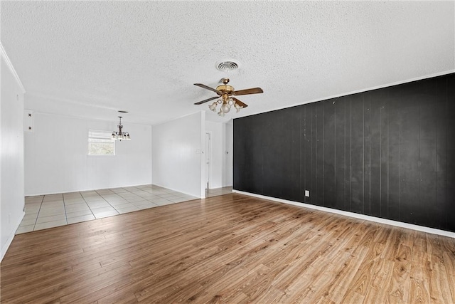 unfurnished room featuring ceiling fan with notable chandelier, a textured ceiling, and light wood-type flooring