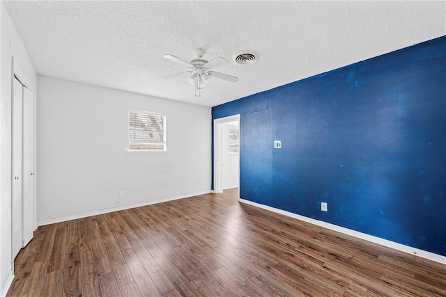 unfurnished room with ceiling fan, wood-type flooring, and a textured ceiling