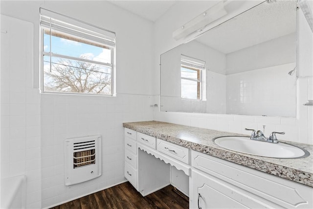 bathroom with vanity, hardwood / wood-style floors, heating unit, and tile walls