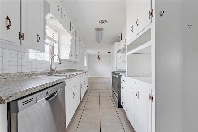 kitchen featuring sink, light tile patterned floors, appliances with stainless steel finishes, white cabinets, and decorative backsplash