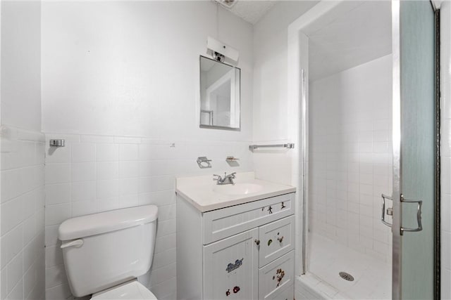 bathroom featuring vanity, toilet, a shower with door, and tile walls