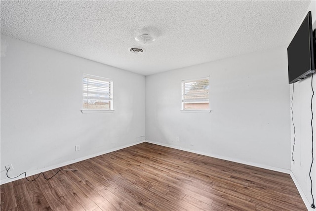 empty room with dark hardwood / wood-style floors and a textured ceiling