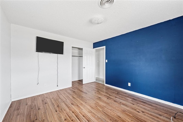 unfurnished bedroom with a closet, a textured ceiling, and light wood-type flooring