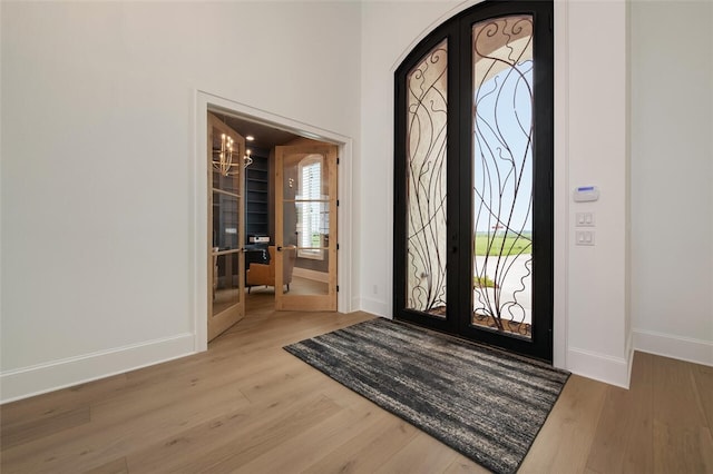 entryway with a chandelier, french doors, and light hardwood / wood-style floors