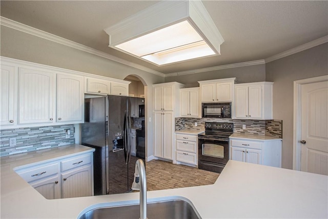 kitchen with white cabinetry, sink, backsplash, black appliances, and ornamental molding