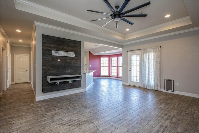 unfurnished living room featuring a raised ceiling, ceiling fan, ornamental molding, and hardwood / wood-style flooring