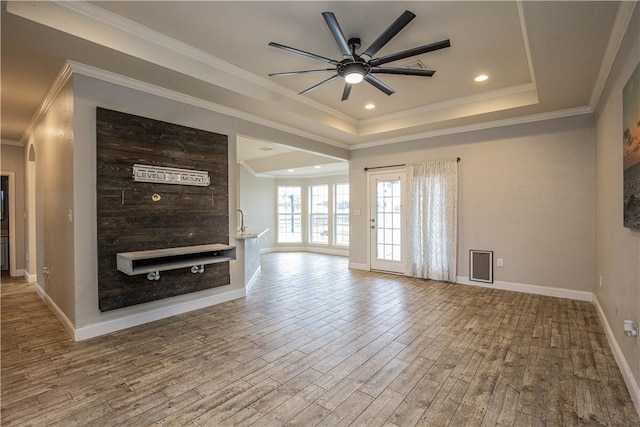 unfurnished living room with a tray ceiling, ornamental molding, ceiling fan, and wood-type flooring