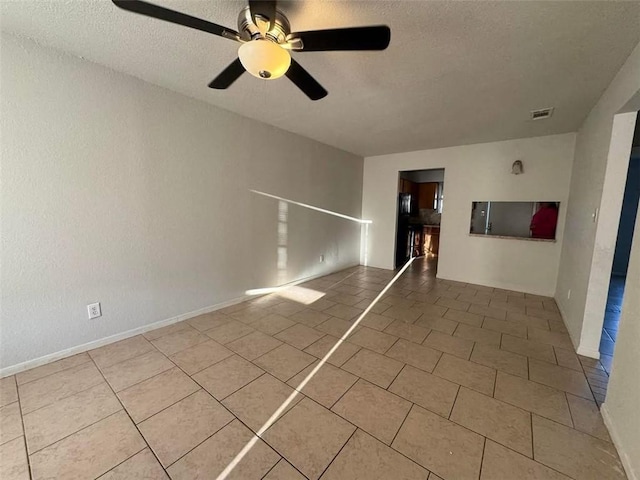 tiled empty room with visible vents, a textured ceiling, and ceiling fan