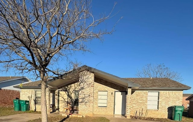 exterior space featuring brick siding and a shingled roof