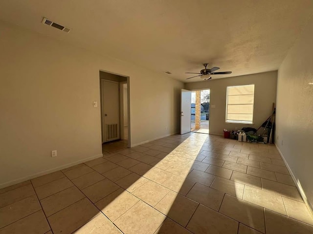 spare room featuring tile patterned floors, visible vents, baseboards, and ceiling fan