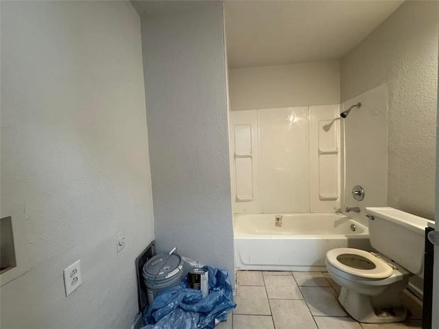 bathroom featuring tile patterned flooring, toilet, a textured wall, and shower / washtub combination