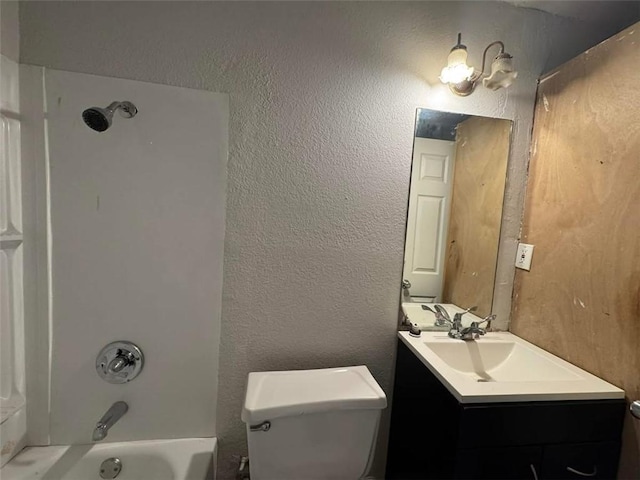 full bath featuring toilet, vanity, bathtub / shower combination, and a textured wall