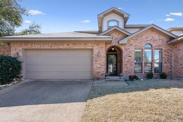 view of front of property featuring a front lawn, concrete driveway, brick siding, and an attached garage