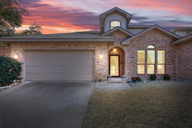 view of front facade with an attached garage, driveway, and brick siding