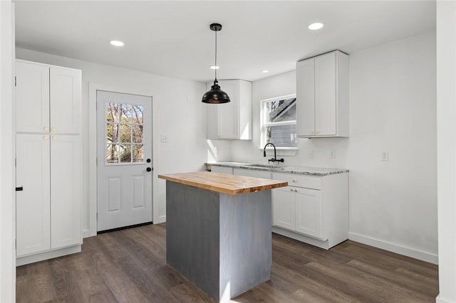 kitchen with dark wood-style floors, wooden counters, a sink, and white cabinets