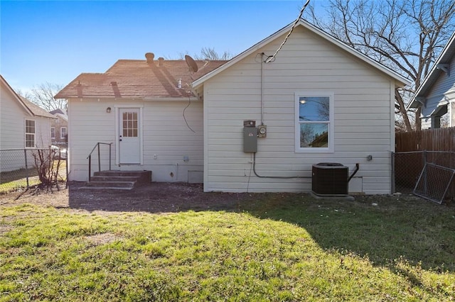 rear view of house with cooling unit, a fenced backyard, a yard, and entry steps