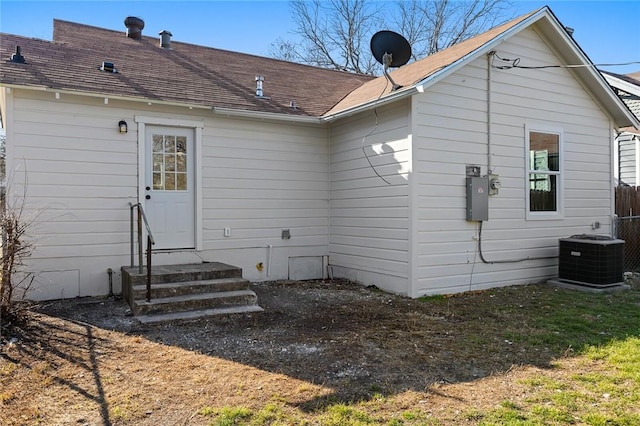 back of house featuring central air condition unit, roof with shingles, fence, and entry steps