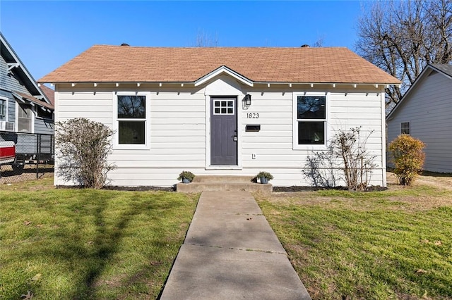 bungalow-style home featuring fence and a front lawn