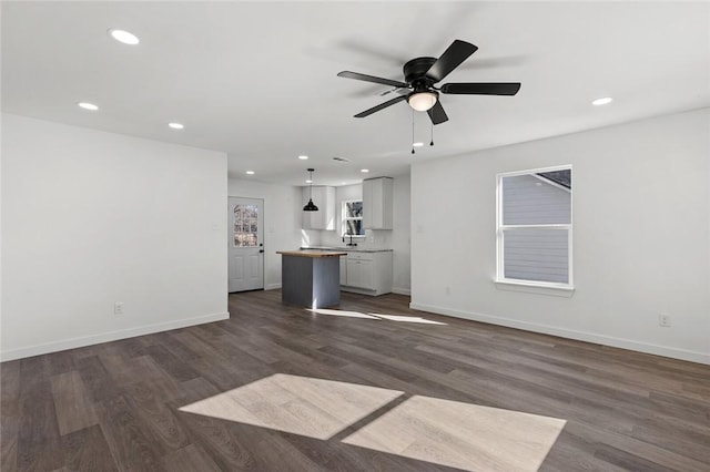 unfurnished living room featuring dark wood-style flooring, recessed lighting, and baseboards