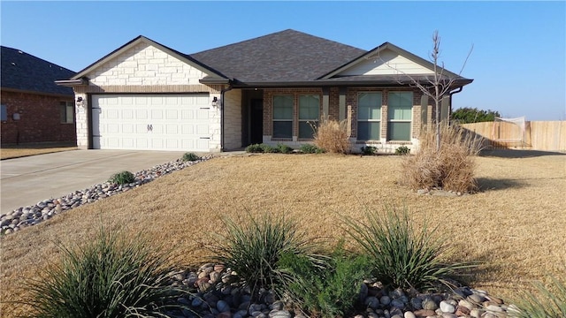 view of front facade with a garage, brick siding, fence, driveway, and roof with shingles