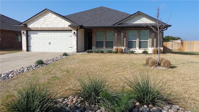 view of front facade with brick siding, an attached garage, concrete driveway, and fence