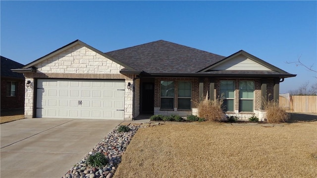 view of front facade with driveway, a shingled roof, stone siding, an attached garage, and brick siding