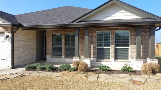 exterior space with brick siding, an attached garage, and a shingled roof