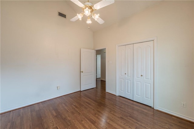 unfurnished bedroom with dark hardwood / wood-style flooring, high vaulted ceiling, a closet, and ceiling fan