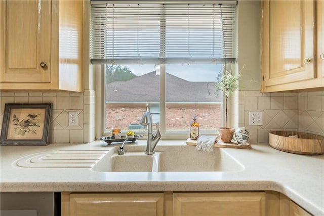 kitchen with light brown cabinetry, backsplash, and sink