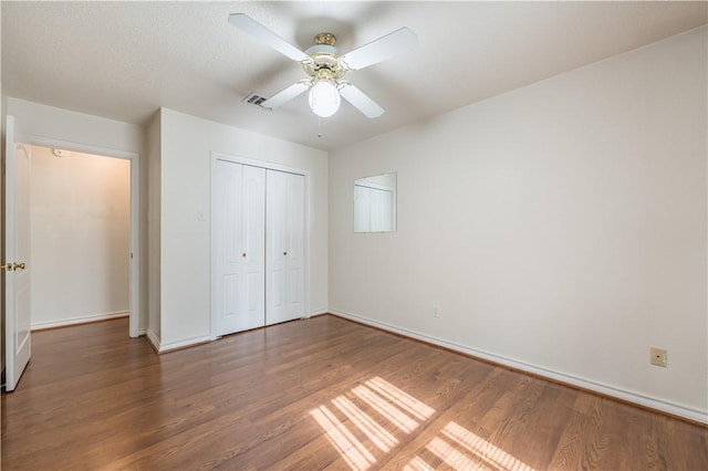 unfurnished bedroom with dark wood-type flooring, ceiling fan, and a closet