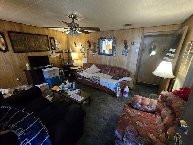 carpeted living room featuring ceiling fan and wood walls