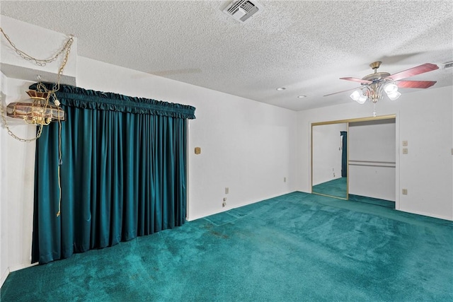 empty room featuring ceiling fan, carpet, and a textured ceiling