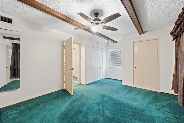 interior space featuring carpet floors, ceiling fan, beamed ceiling, and a textured ceiling