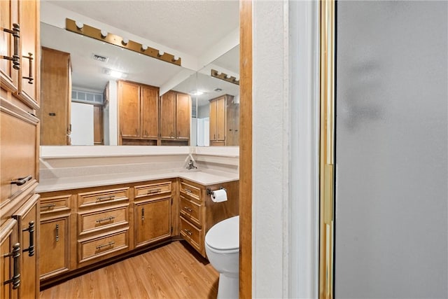 bathroom featuring vanity, wood-type flooring, an enclosed shower, and toilet