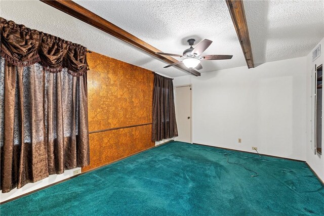 carpeted spare room with beam ceiling, ceiling fan, and a textured ceiling