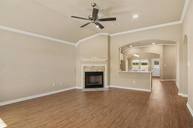 unfurnished living room featuring dark hardwood / wood-style flooring, ornamental molding, vaulted ceiling, ceiling fan, and a fireplace