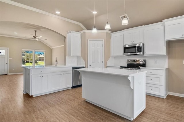 kitchen with vaulted ceiling, ceiling fan, appliances with stainless steel finishes, a kitchen island, and white cabinetry