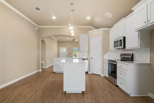 kitchen with wood-type flooring, stainless steel appliances, white cabinetry, and pendant lighting