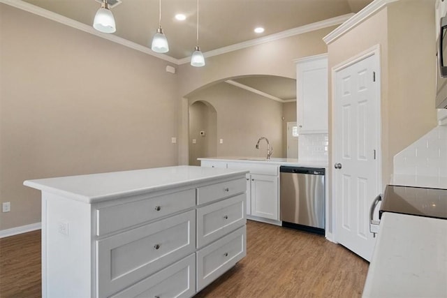 kitchen with appliances with stainless steel finishes, light wood-type flooring, tasteful backsplash, a center island, and white cabinetry