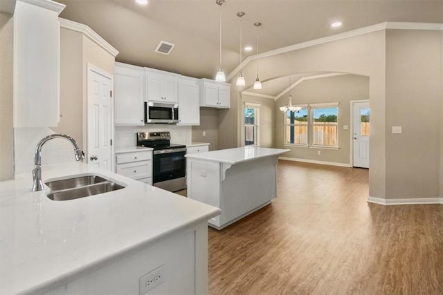 kitchen featuring stainless steel appliances, vaulted ceiling, sink, decorative light fixtures, and white cabinets