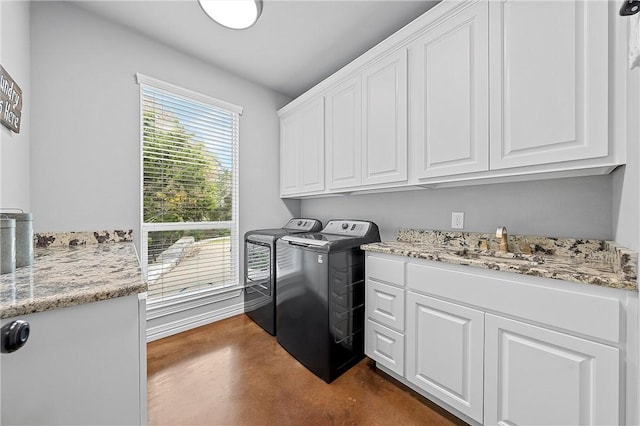 clothes washing area with washer and clothes dryer and cabinets