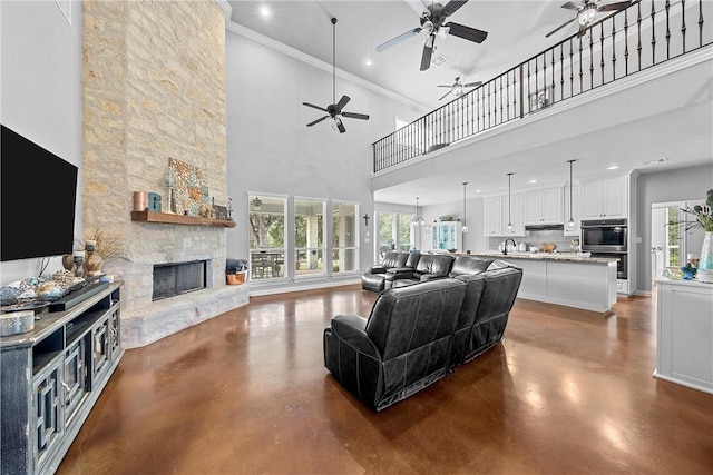 living room featuring a fireplace, a towering ceiling, ornamental molding, and sink